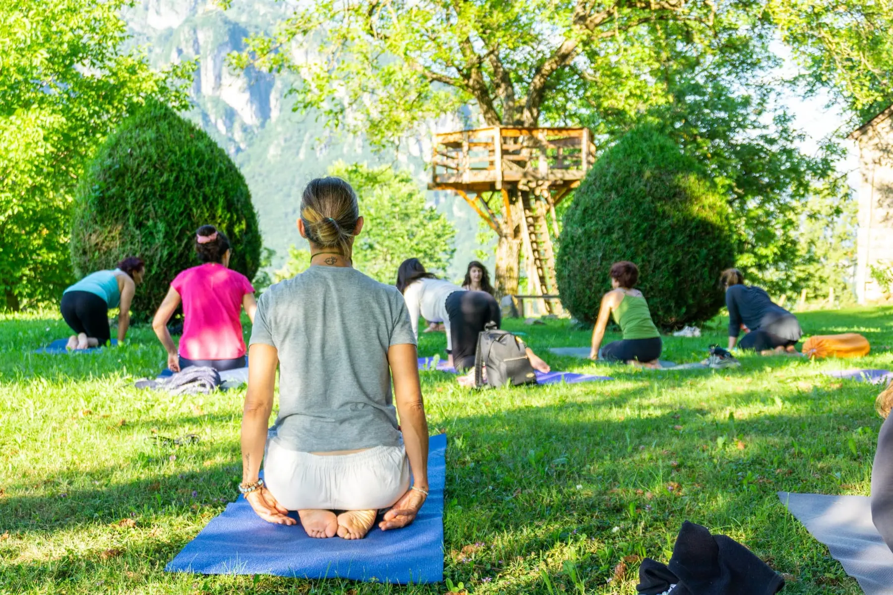 Pratica di yoga sul prato del Borgo Zen, con la casetta sull’albero sullo sfondo