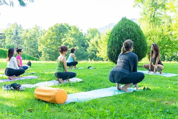 Pratica di yoga sul prato, in posizione accovacciata