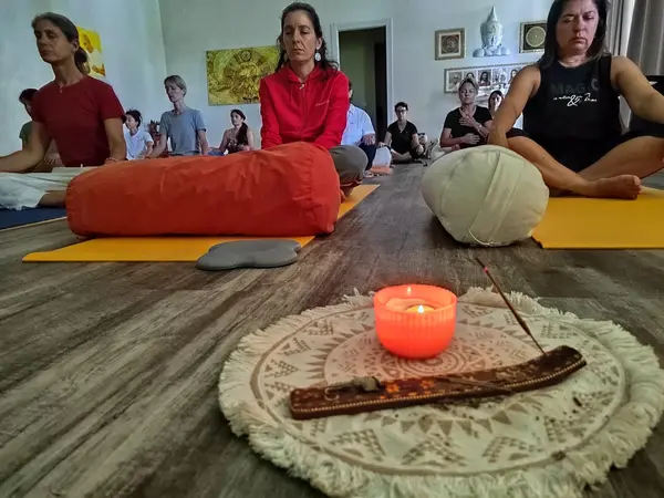 Una candela accesa e un bastoncino d’incenso al centro della sala durante la meditazione