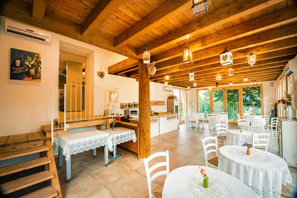Una sala dell’agriturismo con travi in legno e tavoli apparecchiati
