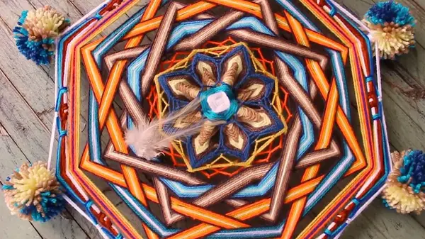 Mandala ottagonale a raggi arancioni, azzurri e marroni con un fiore blu al centro
