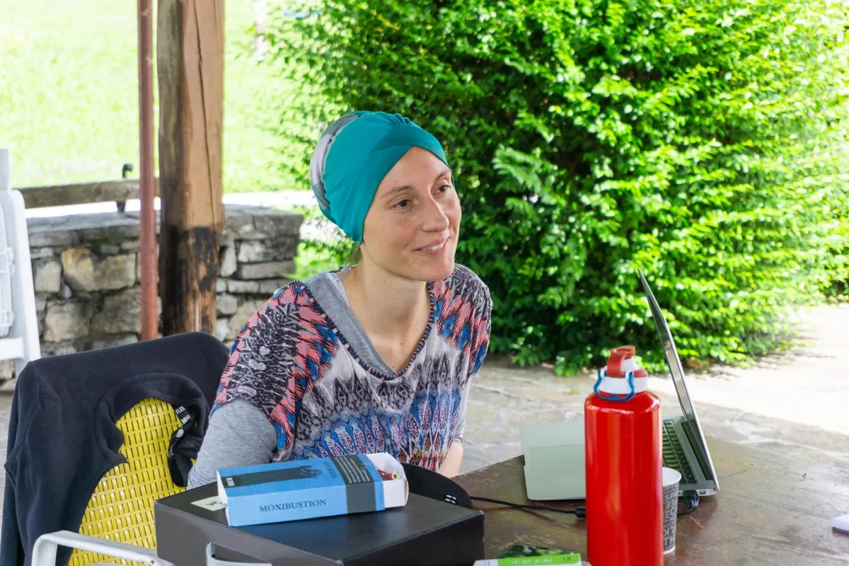 Relatrice con un turbante turchese, seduta a un tavolo sotto un pergolato durante un ritiro